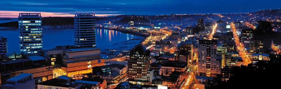 Vista panorámica nocturna de Puerto Montt, con la bahía y las calles iluminadas